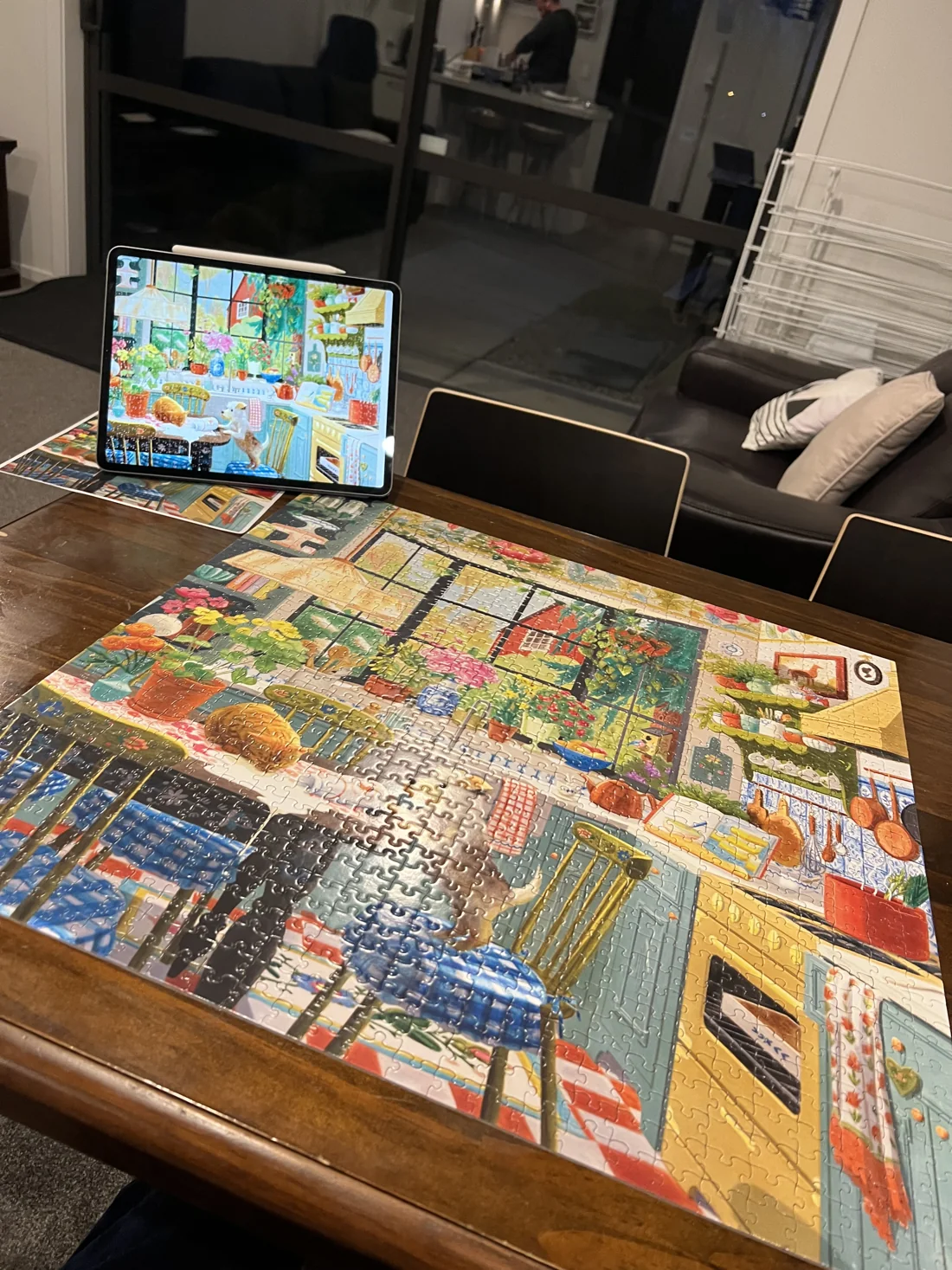 A colourful jigsaw puzzle on a table, with its reference image on a tablet.